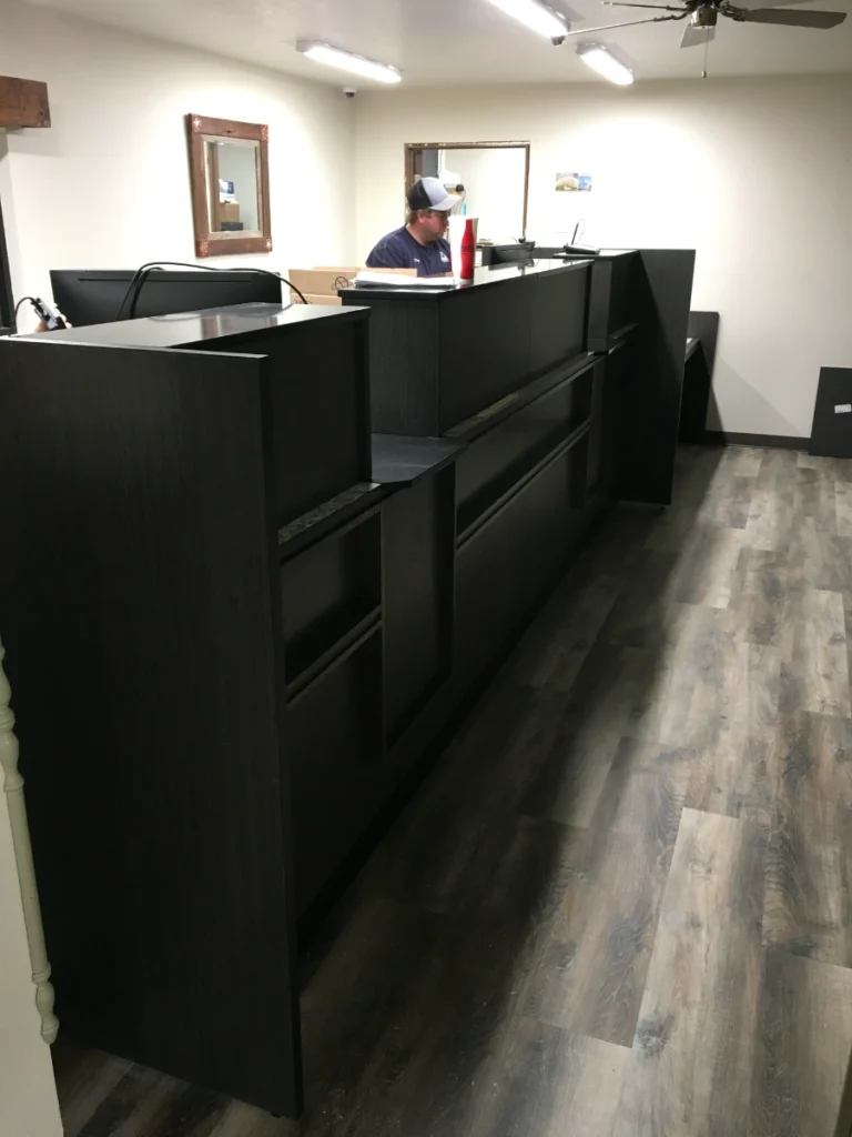 Custom dark wood bank teller line viewed from the customer side during weekend installation