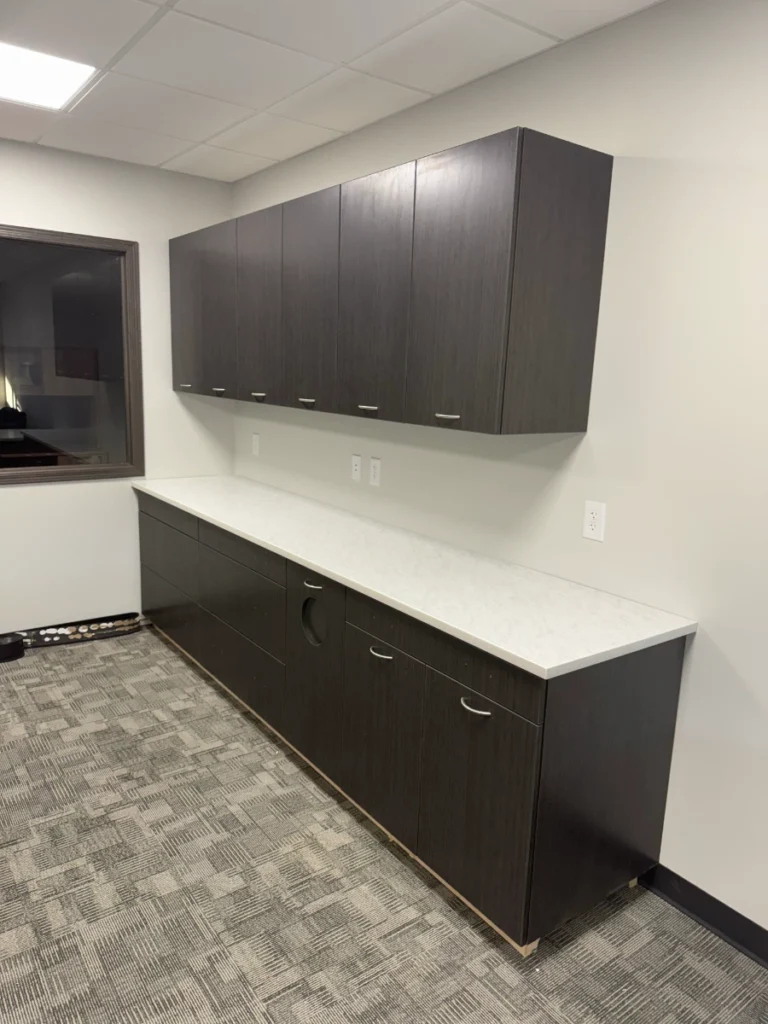 Wall-hung storage cabinets and lower cabinetry with solid surface countertop in a bank back office