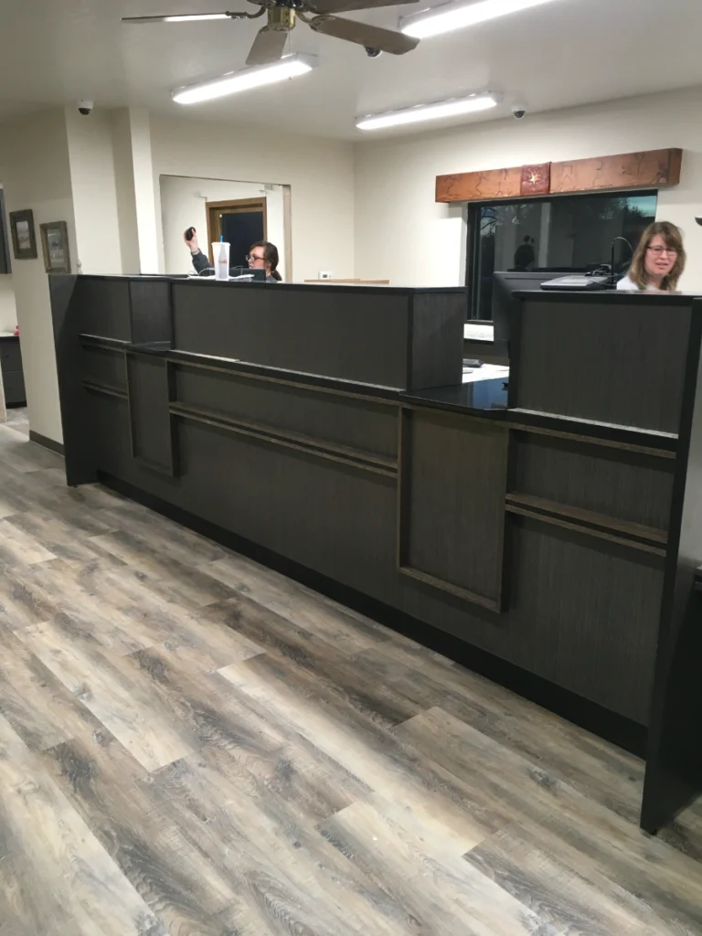 Completed bank teller station with staff working behind the counter on the first day after installation